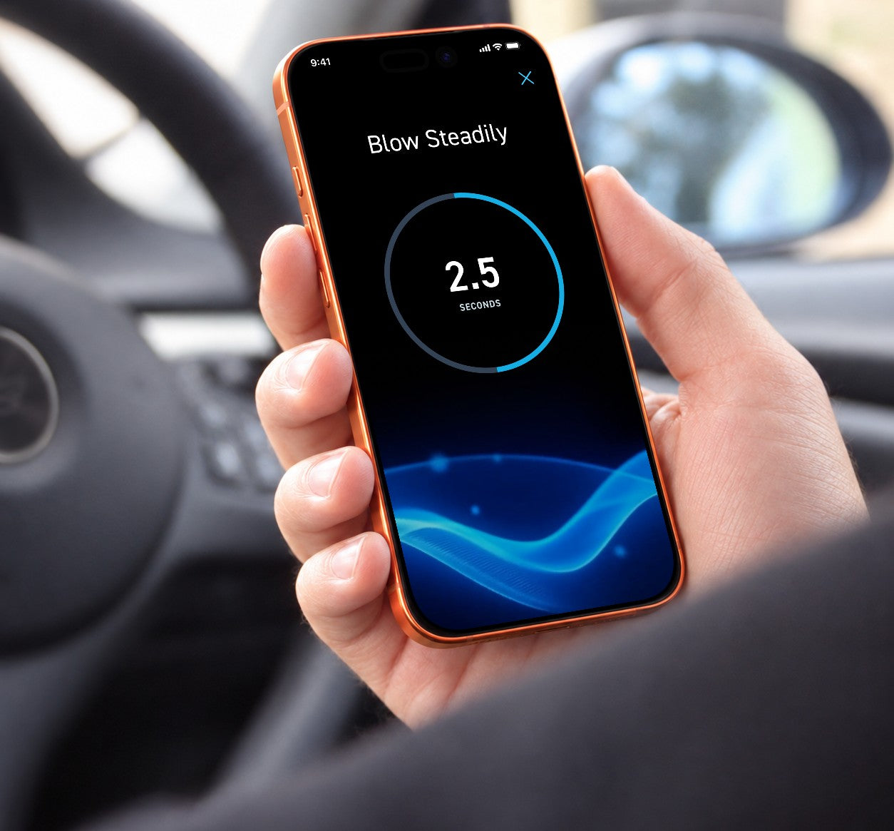 Hand holding an iPhone 17 Pro showing the BACtrack app Blow Steadily screen in a car